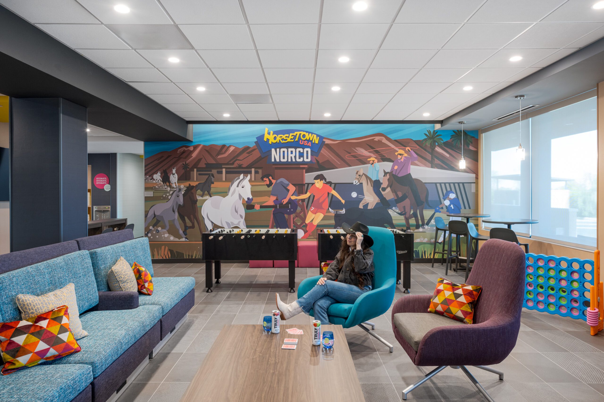 Happy guest sitting in bright hotel lobby with drink and games